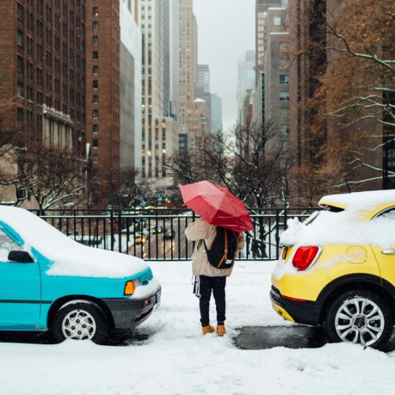 Parken im Winter Person steht zwischen zugescheneiten Autos
