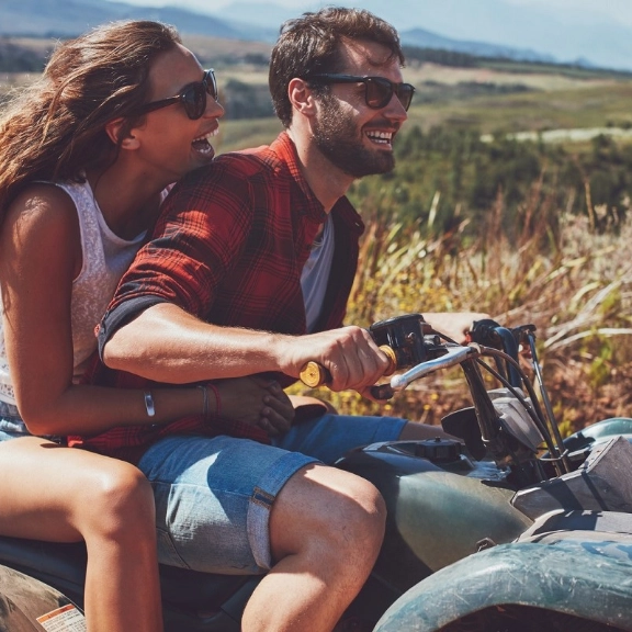 Paar sitzt auf Quad und fährt durch die Landschaft