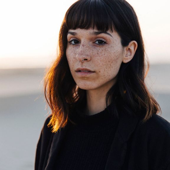 Junge Frau an einem Strand schaut nach vorn