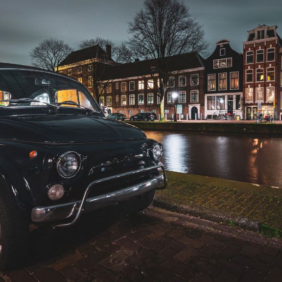 Oldtimer parkt am Kanal in Amsterdam