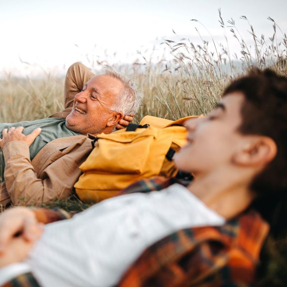 Großvater und Enkel leigen entspannt in einem Feld.