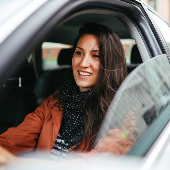 Frau fährt mit geöffnetem Autofenster durch die Stadt.