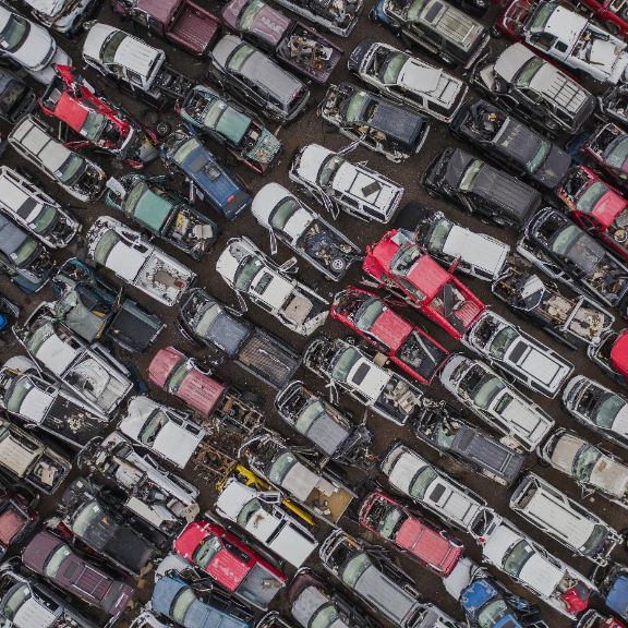 Auto verschrotten – wie entsorge ich mein Fahrzeug? Luftaufnahme eines Schrottplatz mit beschädigten Autos in Reihen.