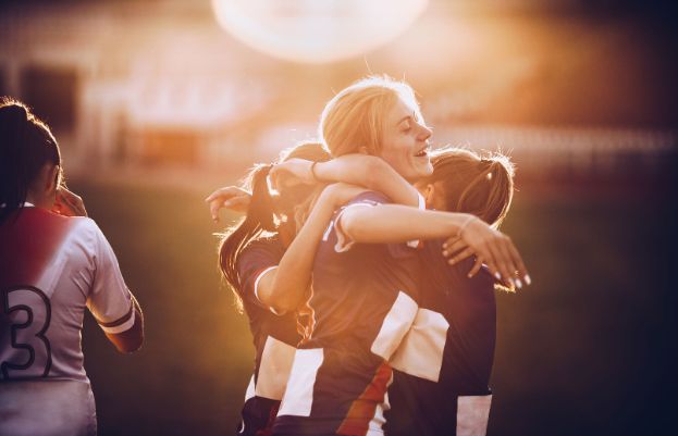 Junge Frauen spielen Fussball und freuen sich