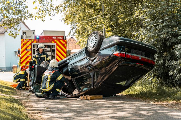 Einsatz bei einem Autounfall. Die Feuerwehrleute üben die patientengerechte Rettung eines Unfallopfers aus einem Auto.