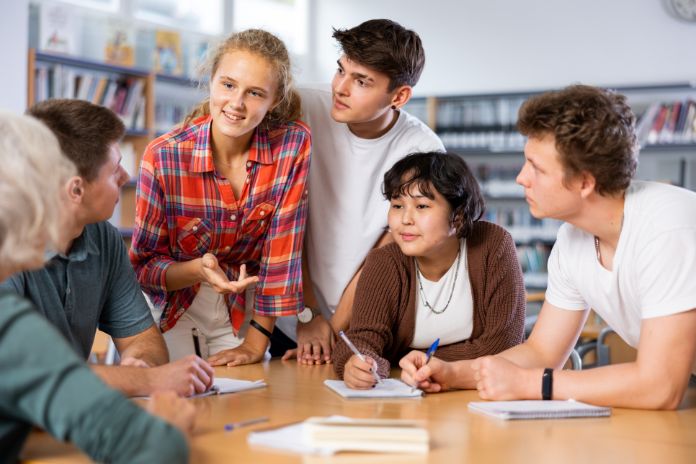 Junge Menschen sitzen an einem Tisch und diskutieren