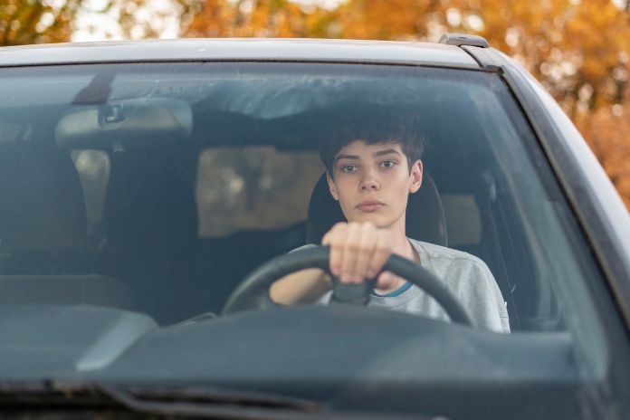 Ein junger Teenager sitzt im Auto und lernt Autofahren.