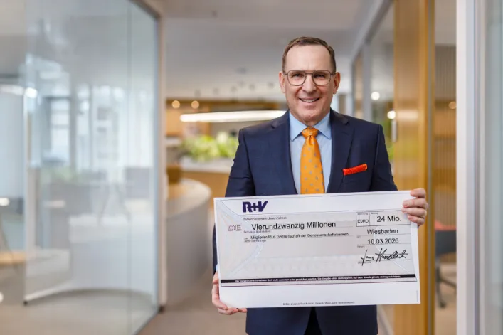 Jens Hasselbächer, Vorstand des Ressorts Kunden & Vertrieb der R+V Versicherung, mit einem symbolischen Cashback-Scheck über rund 24 Millionen Euro für die R+V-Mitglieder-Plus-Kunden