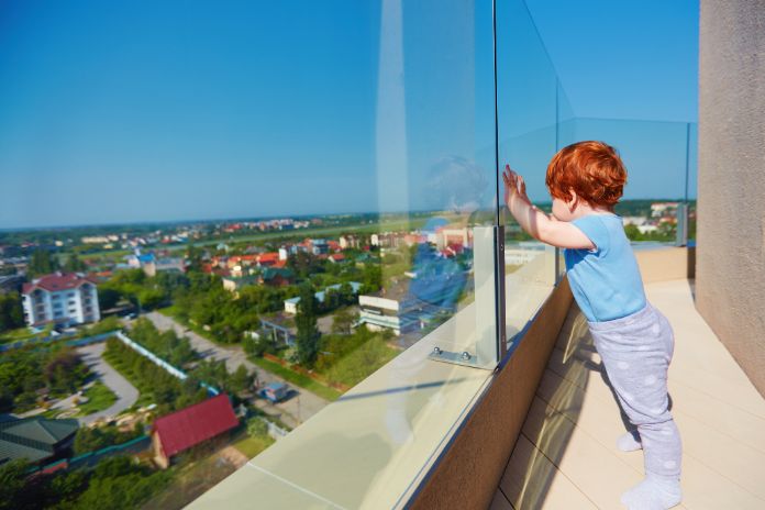 Ein kleiner Junge genießt die Aussicht auf die Stadt von der Dachterrasse eines mehrstöckigen Gebäudes