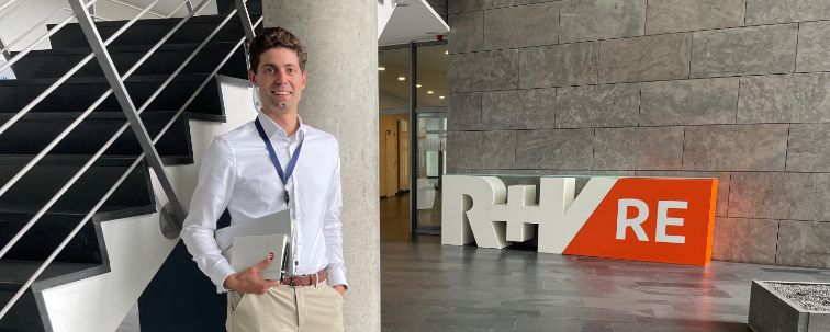 Underwriter Fabia Lassen steh im Treppenhaus vor dem Logo der R+V Re