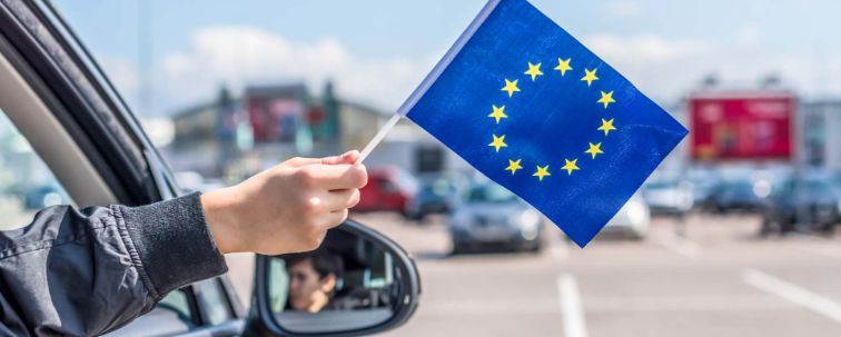 Person hält kleine EU-Fahne aus dem Autofenster.