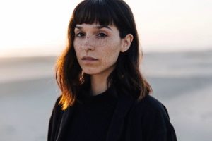 Junge Frau an einem Strand schaut nach vorn