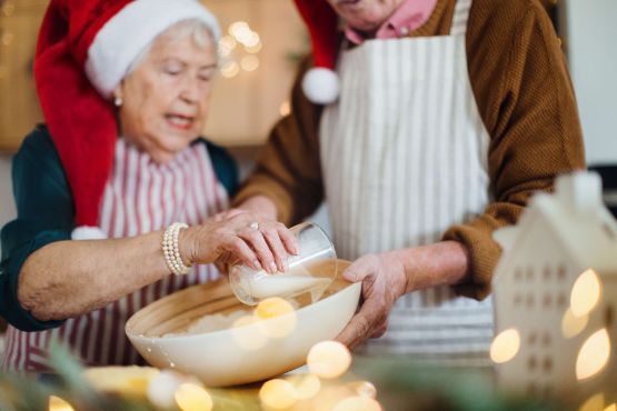 Glueckliche Senioren backen gemeinsam Weihnachtskuchen zu Hause