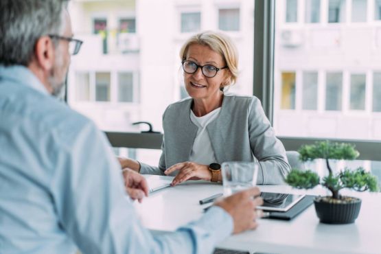 Zwei Personen bei einem Beratungsgespräch mit Laptop und Dokumenten
