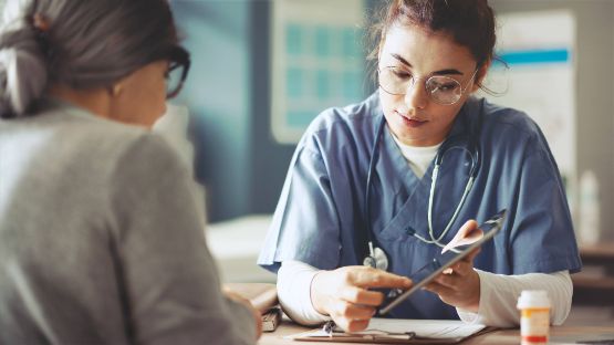 Pflegefachkraft bespricht mit älterer Frau den aktuellen Pflegegrad