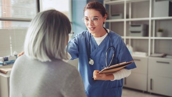 Ärztin prüft Pflegegradeinstufung für eine aeltere grauhaarige Frau