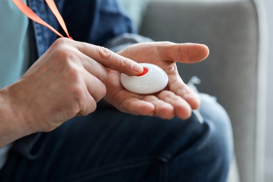 Ein Pflegebedürftiger betätigt den Notfallknopf eines Hausnotrufsystems.