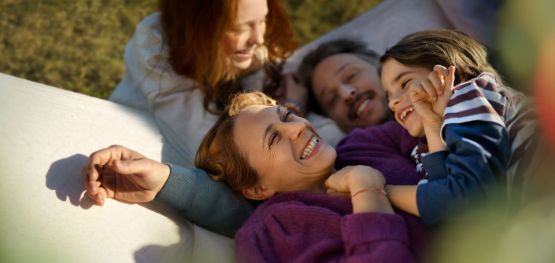 Glückliche Familie mit 2 Kindern tobt im Garten 