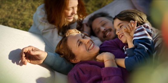 Glückliche Familie mit 2 Kindern tobt im Garten 