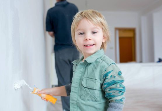 Kind streicht eine Wand in der Wohnung