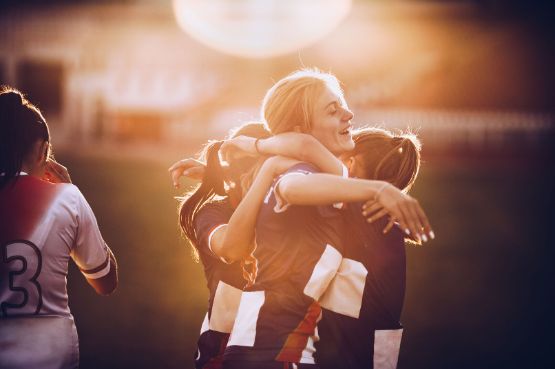 Junge Frauen spielen Fussball und freuen sich