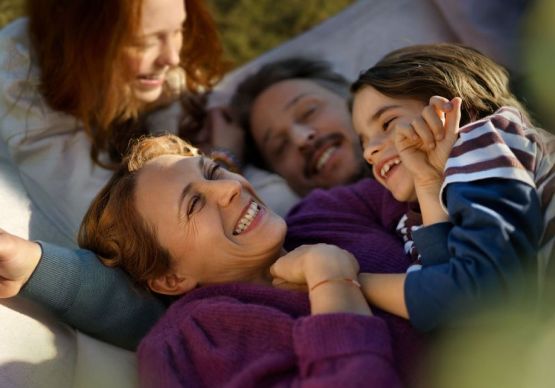 Eine Familie mit zwei Kindern liegt vergnügt in einer Hängematte.