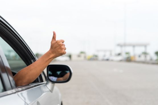Beifahrer eines PKW streckt seine Hand mit Daumen hoch aus dem Fenster
