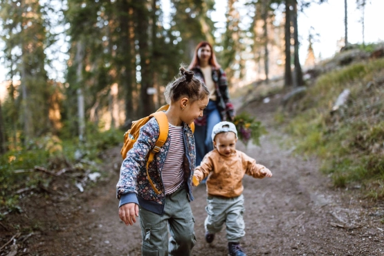 Eine Familie mit Kindern geht im Wald spazieren.