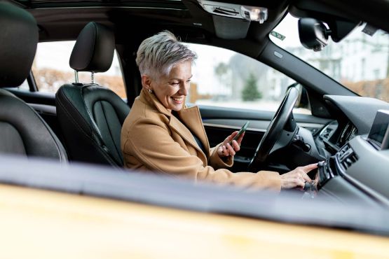 Frau bedient das Infotainment-System im Auto.