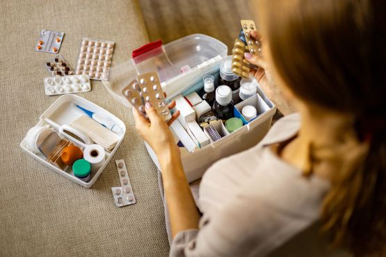 Elternteil kontrolliert die Hausapotheke für Babys in einer kindersicher verstauten Box.