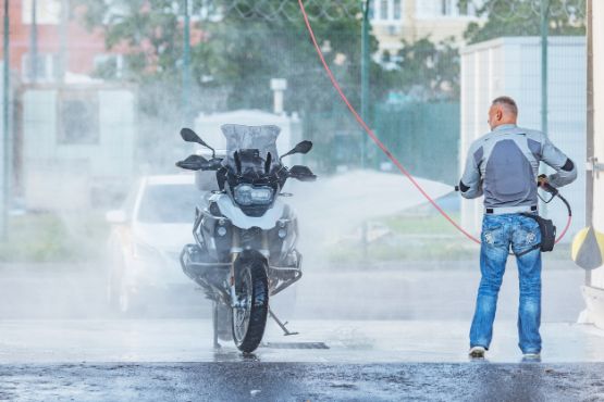 Ein Fahrer wäscht sein Motorrad in der Waschanlage. 