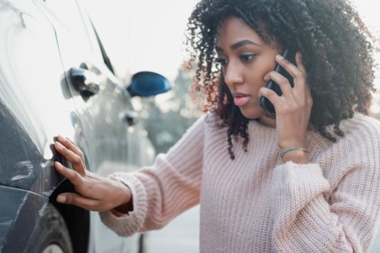 Frau mit Schrammen am Auto