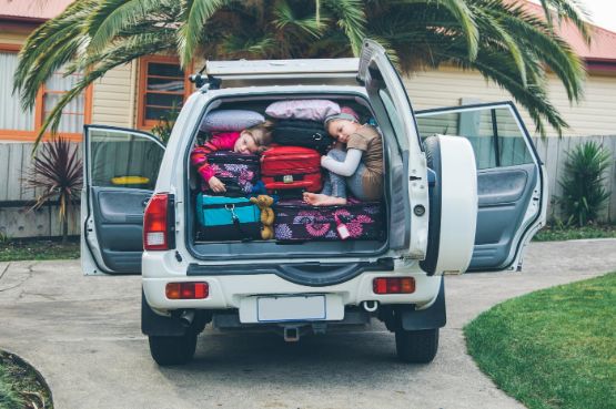 Zwei Kinder im voll beladenen Kofferraum eines Jeeps.