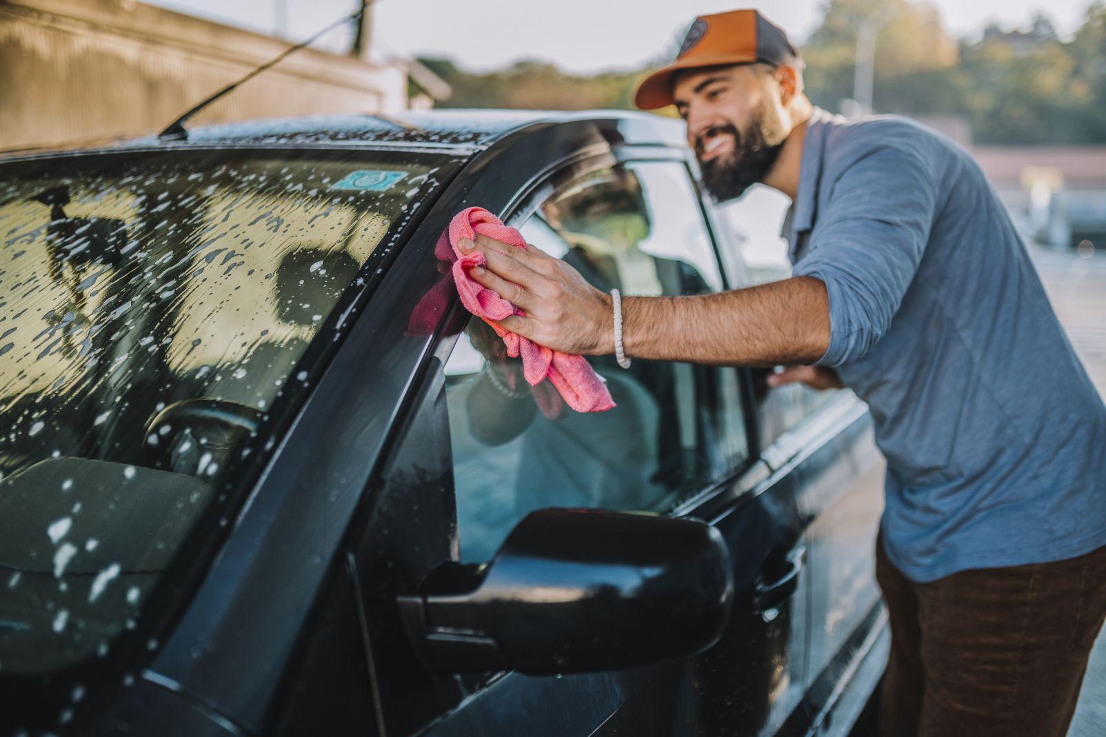Mann wäscht Auto per Hand.