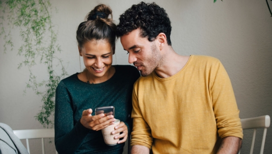 Ein Paar schaut gemeinsam auf ein Smartphone.