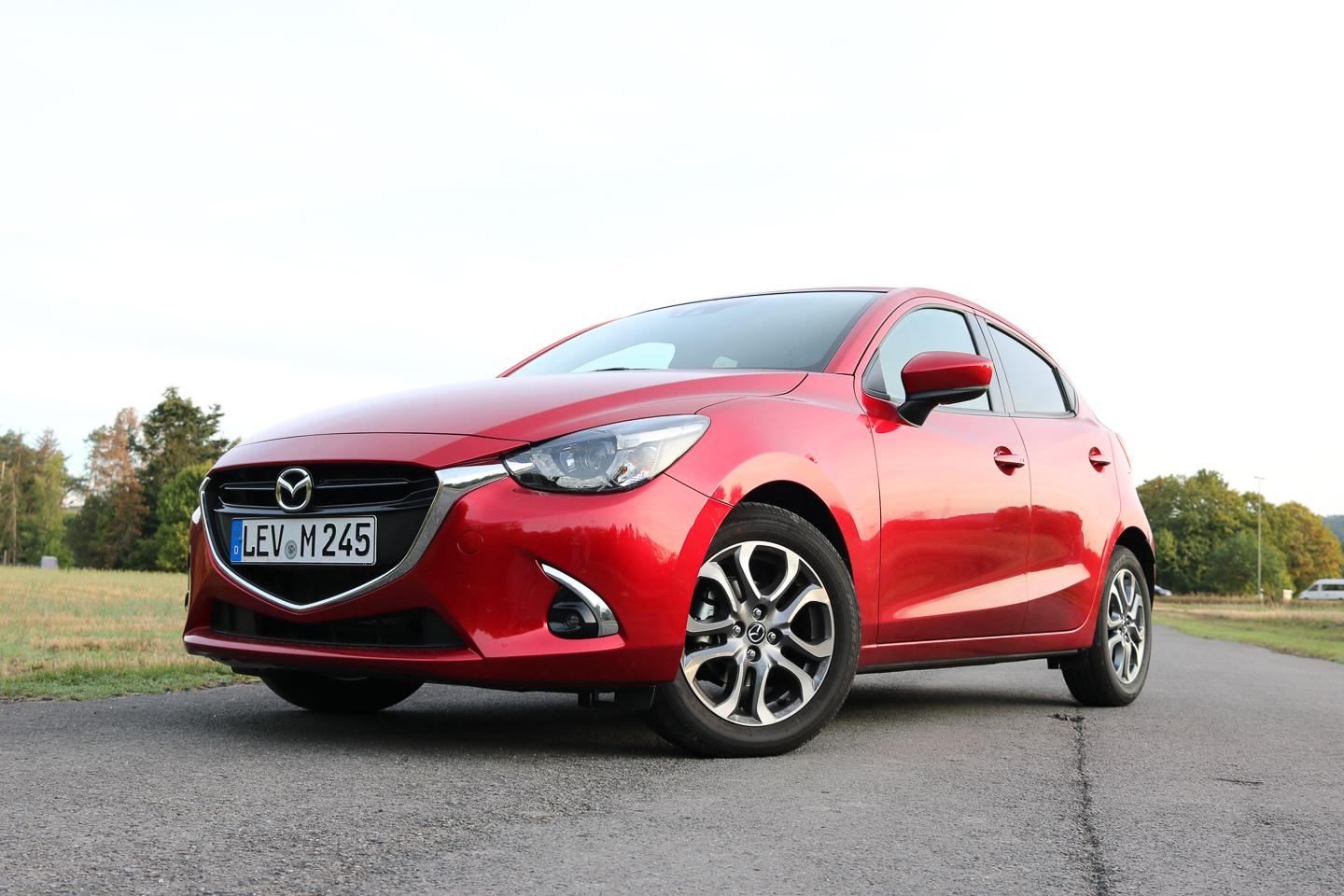 Roter Mazda2 Kleinwagen auf Parkplatz, Seitenansicht mit Blick auf Frontdesign und Räder