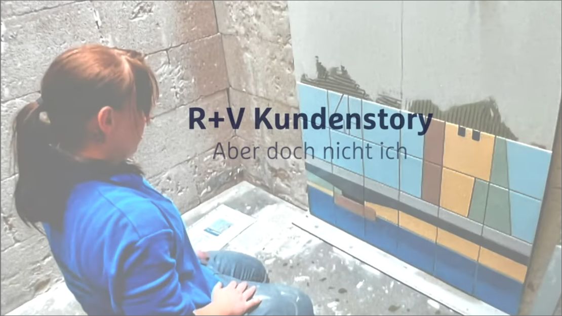 R+V Kundenstory "Aber doch nicht ich". Fliesenlegerin kniet vor einem Wandbild aus Fließen, das halb fertig ist.