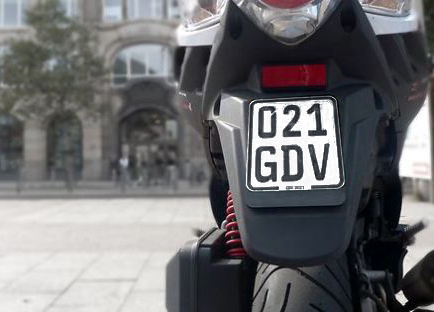 Rückseite eines Rollers mit einem schwarzen Versicherungskennzeichen.