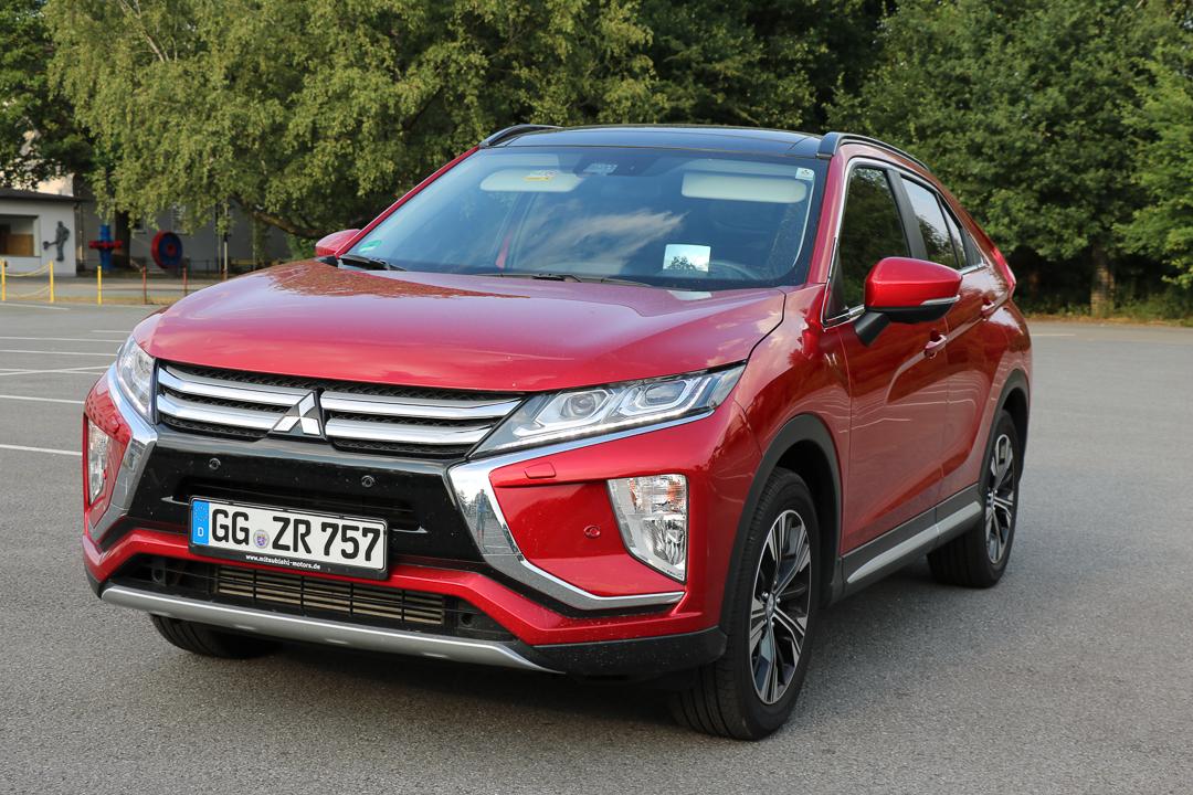 Roter Mitsubishi Eclipse Cross SUV parkt auf Parkplatz, Waldkulisse im Hintergrund, deutsches Kennzeichen